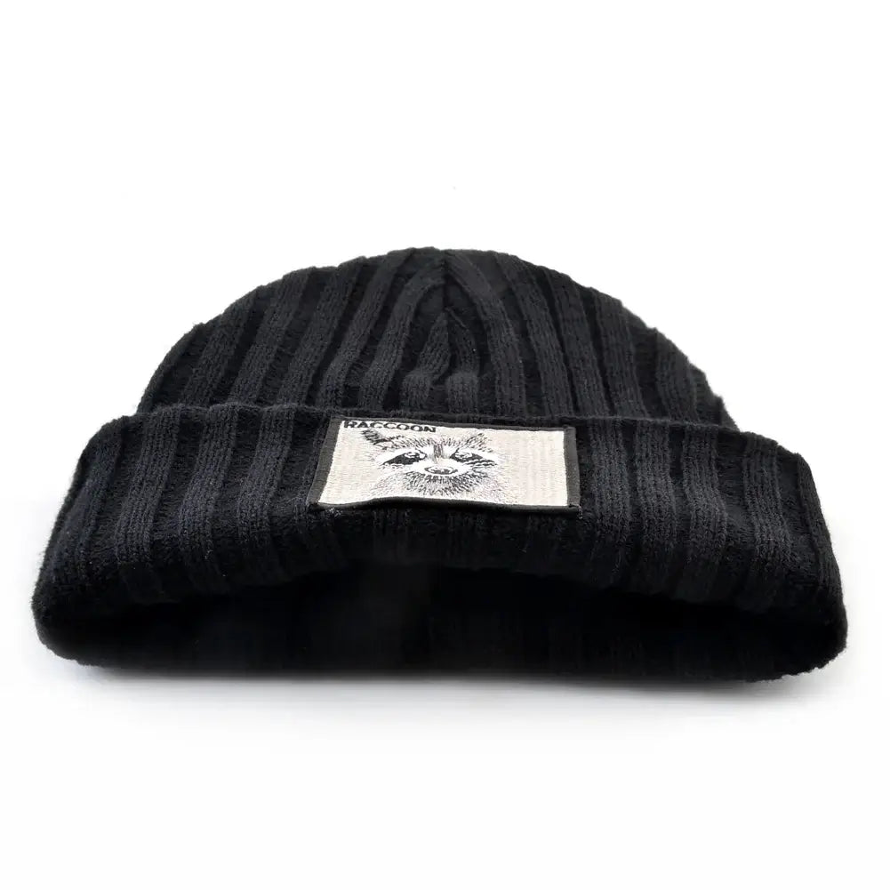 Close-up of black ribbed knit beanie with embroidered raccoon patch, warm unisex winter accessory for cold days