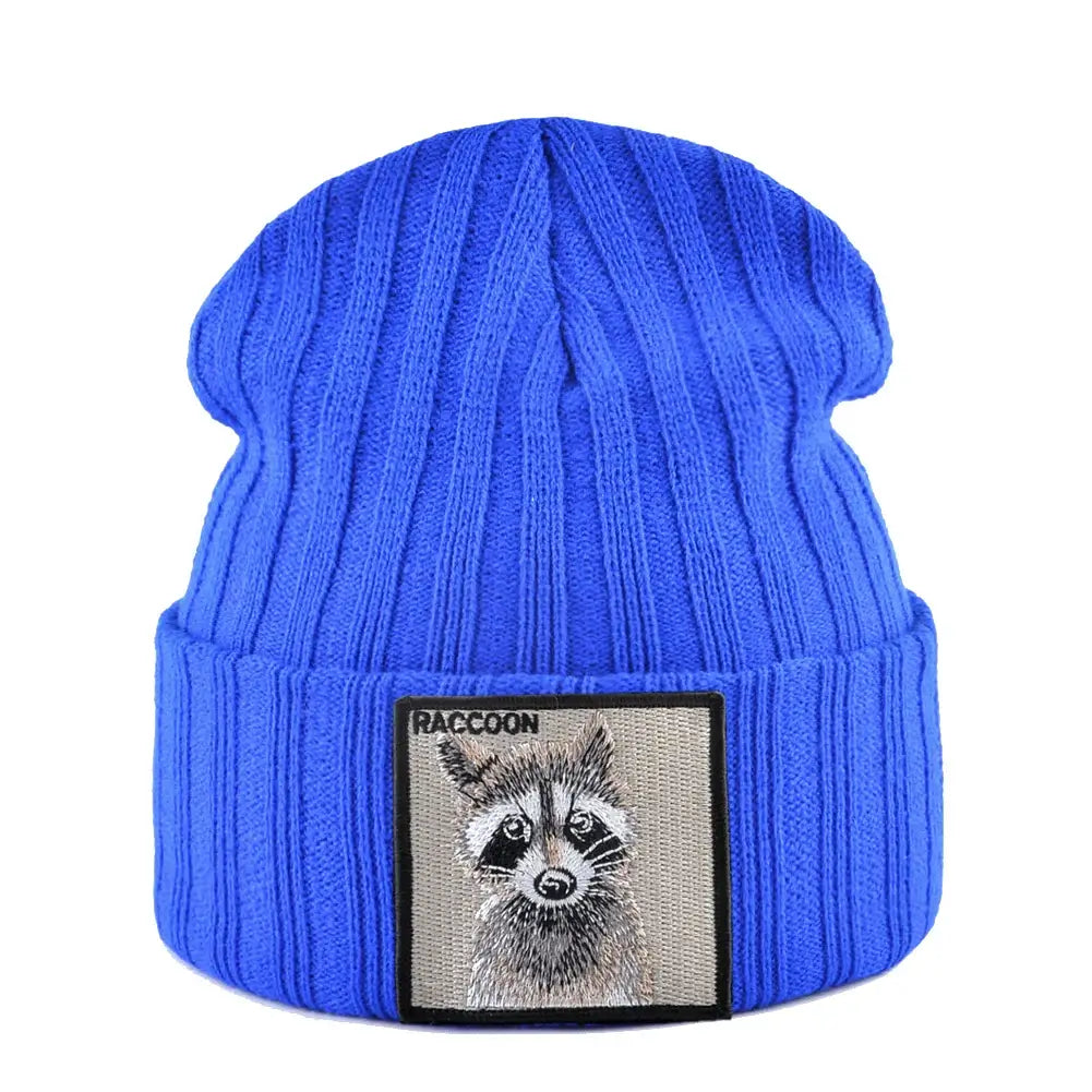 Blue ribbed knit beanie with raccoon patch, measuring 23cm height and 22cm width, featuring a raccoon illustration patch, suitable for cold weather.