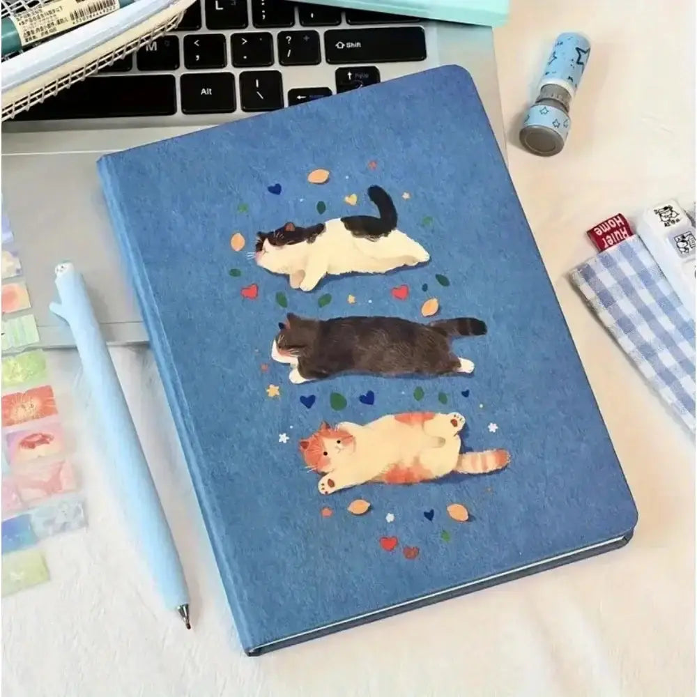 Katzen-Notizbuch A5 Hardcover mit niedlichem Katzen-Design auf blauer Oberfläche, ideal für Notizen und kreative Arbeiten.