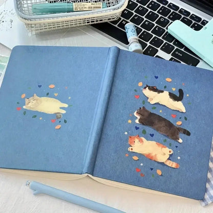 Katzen-Notizbuch A5 Hardcover mit süßem Katzen-Design auf blauer Oberfläche und dekorativen Herzen.