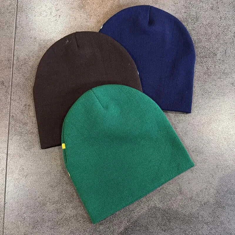 Set of three knitted winter hats in blue, green, and black with dragon design, made of warm material, perfect for cold seasons.