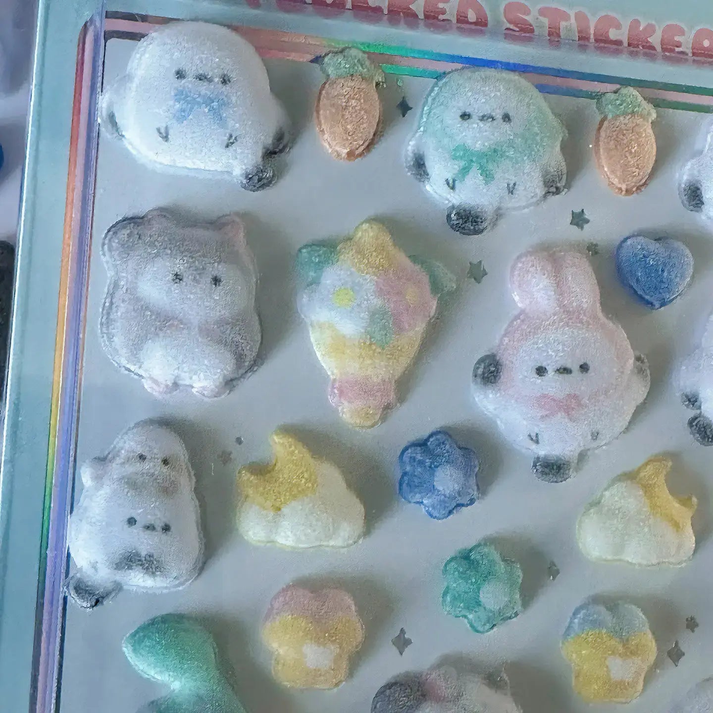 Close-up of glittery 3D animal stickers resembling bears, rabbits, and other animals with shiny, textured surfaces.