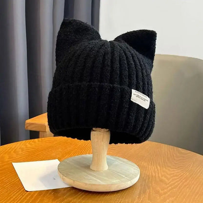 Katzenohren Beanie – Schwarze Strickmütze mit Katzenohren auf einem Holzständer, perfekt für Herbst und Winter.