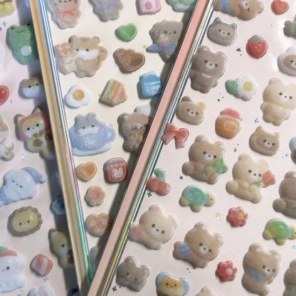 Assorted pastel 3D animal stickers with glitter, featuring bears, rabbits, and hearts, on holographic sticker sheets.