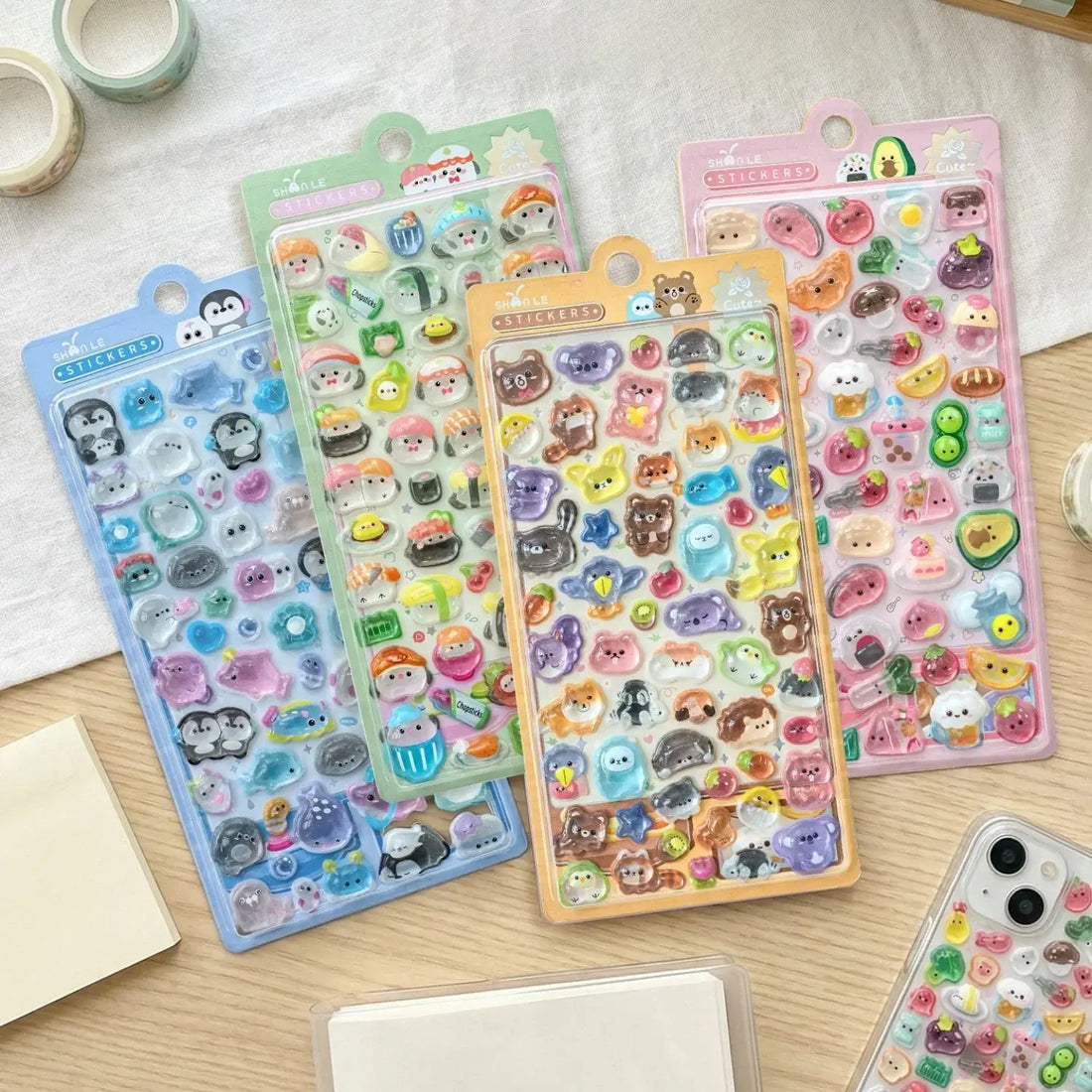 Colorful 3D kawaii sticker set featuring cute animal faces, food items, and accessories in transparent plastic sheets, perfect for decorating notebooks and phones.